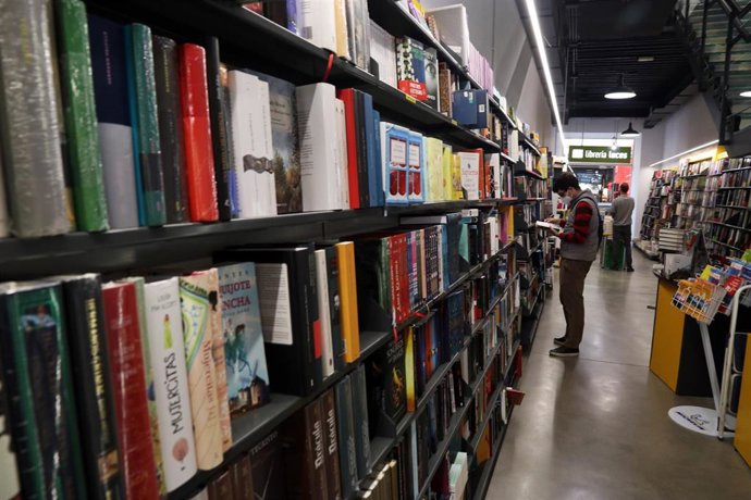 Archivo - Varias personas ojean libros en una librería de la capital de Málaga.  
