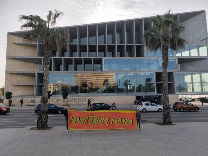 Activistas despliegan una pancarta frente al Palacio de Congresos con motivo de la cumbre turística.