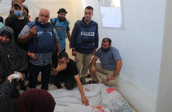 Varios reporteros, entre ellos Wael al Dahdú, de Al Yazira, junto a los cadáveres de sus hijos.