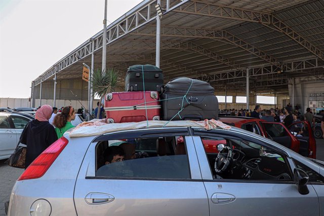 Un grupo de personas espera para abandonar la Franja de Gaza a través del paso de Rafá, en la frontera con Egipto