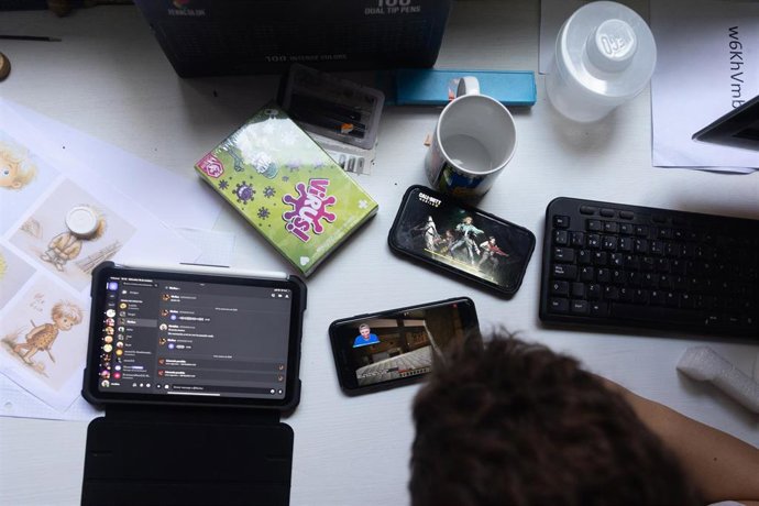 Varios dispositivos móviles colocados sobre la mesa frente a un niño.