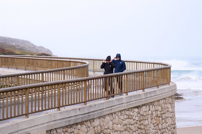 Dos hombres caminan en Santander azotados por el viento