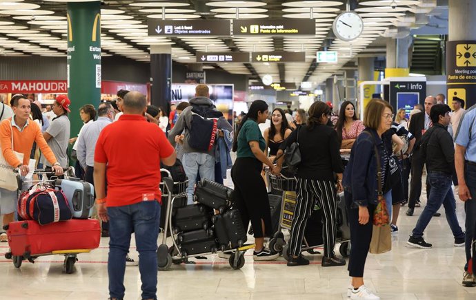 Archivo - Varias personas con maletas en el Aeropuerto Adolfo Suárez-Madrid Barajas.