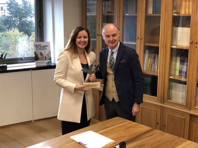 La consejera de Familia, Juventud y Asuntos Sociales, Ana Dávila, recibe un reconocimiento de parte del decano del Colegio Oficial de la Psicología de Madrid, José Antonio Luengo.