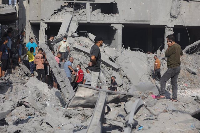 Un grupo de palestinos entre edificios destruidos por los bombardeos del Ejército de Israel contra la Franja de Gaza