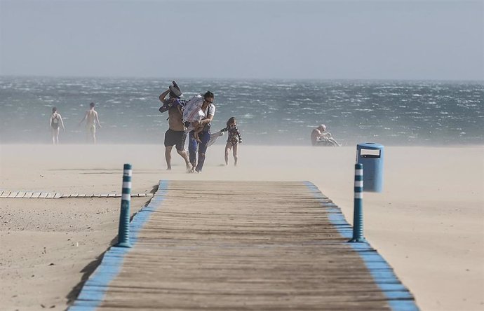 Varias personas en la playa de la Malvarrosa con fuertes rachas de viento