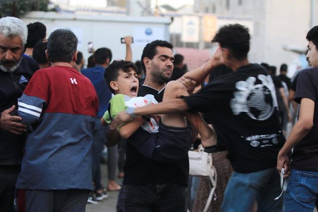 Un hombre palestino evacúa a un niño herido tras un bombardeo israelí en los alrededores del hospital Al Shifa, en el norte de la Franja de Gaza