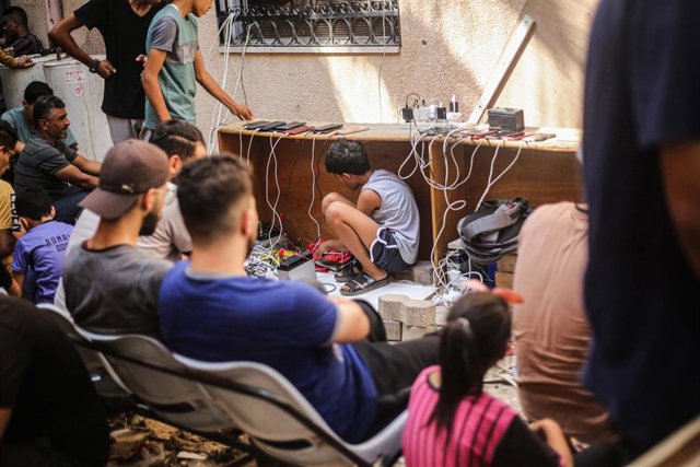 Palestinos acogidos en un hospital en la Franja de Gaza cargando el teléfono móvil