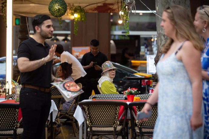 Archivo - Un camarero trata de captar a unas turistas para comer en su restaurante