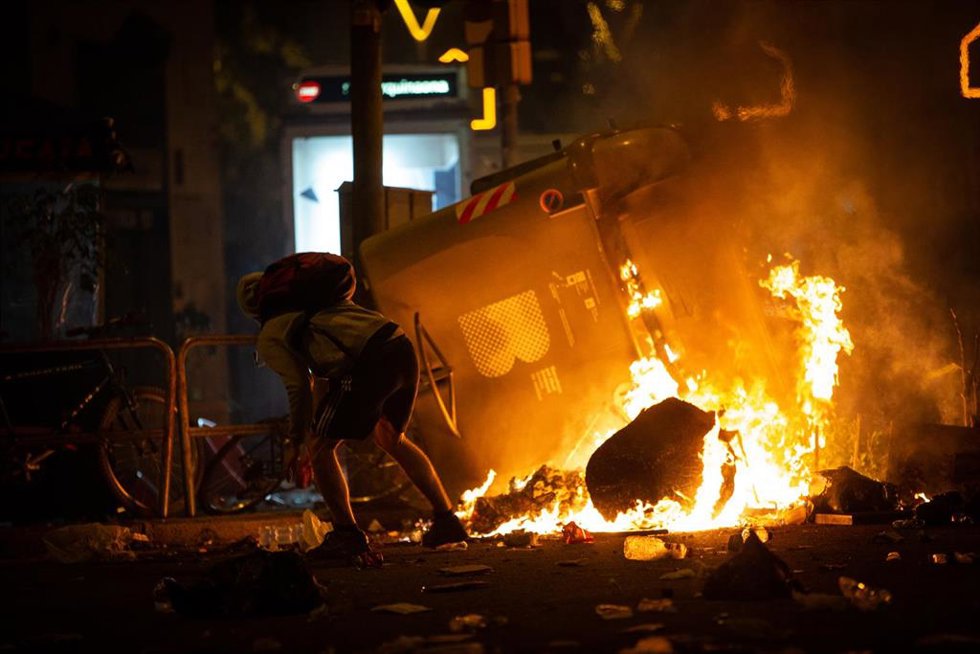 Archivo - Un manifestante frente a un contenedor que arde durante los disturbios en la Plaza de Urquinaona, en Barcelona a 18 de octubre de 2019.