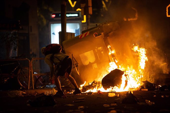 Archivo - Un manifestante frente a un contenedor que arde durante los disturbios en la Plaza de Urquinaona, en Barcelona a 18 de octubre de 2019.