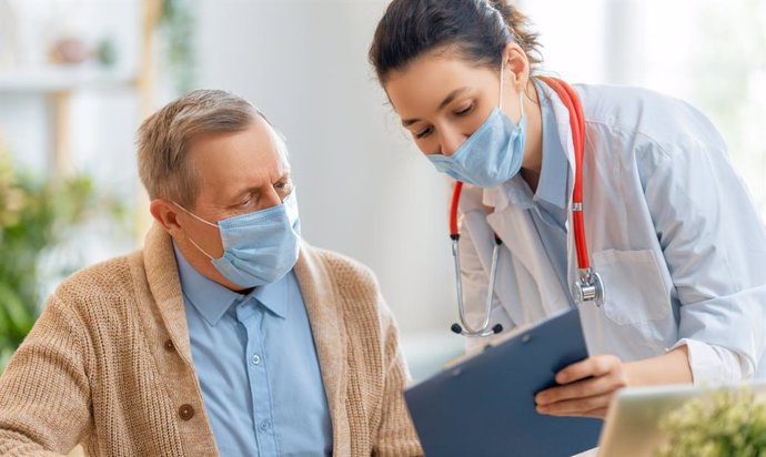 Archivo - Paciente y médico con mascarilla en la consulta por covid persistente.