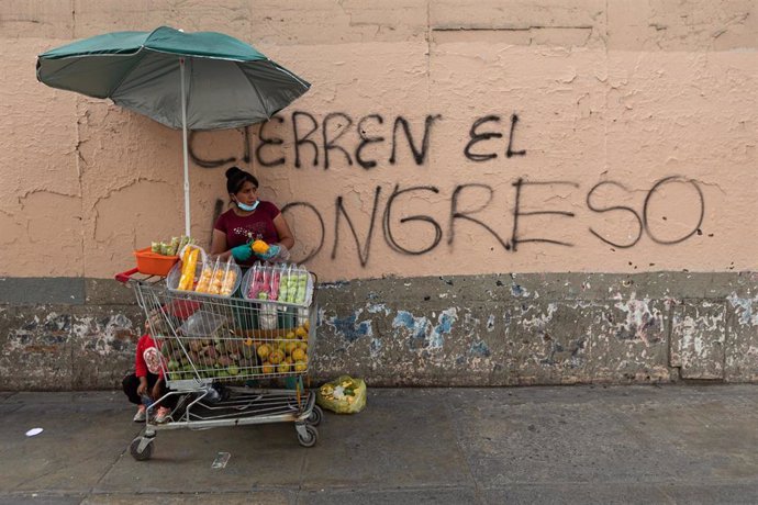 Archivo - Una vendedora ambulante ante una pintada contra el Congreso en Perú, en diciembre de 2022