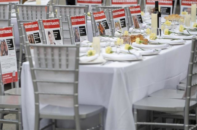 Una mesa con 241 sillas vacías para simbolizar la espera por el regreso de los rehenes capturados por Hamás, frente al Congreso de los Diputados.