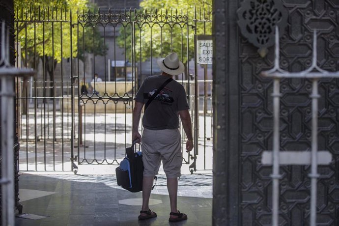 Archivo - Un turista observa el Patio de los Naranjos desde la salida de la Catedral. En Sevilla (Andalucía, España), a 27 de agosto de 2020.