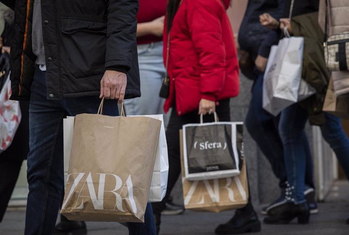 Archivo - Varias personas con bolsas de la compra en una calle centrica