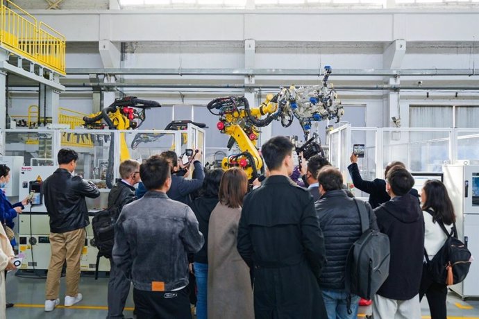 Observers watch industrial robots working based on instructions wirelessly transmitted at high speeds via 5G-Advanced indoor base stations