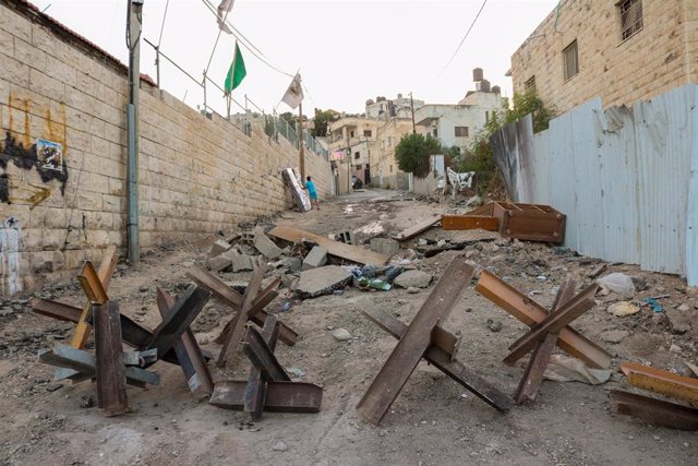 Un niño mueve un colchón a lo largo de una carretera dañada en el campo de refugiados de Yenín después de que las fuerzas israelíes entraran en el campo con excavadoras y tanques