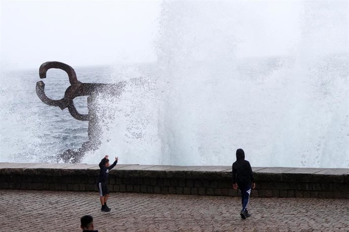 Varias personas se mojan con las olas en el Peine del Viento