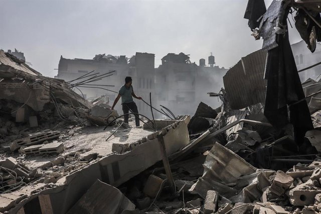 Una persona rastrea los escombros de un edificio destruido en la Ciudad de Gaza