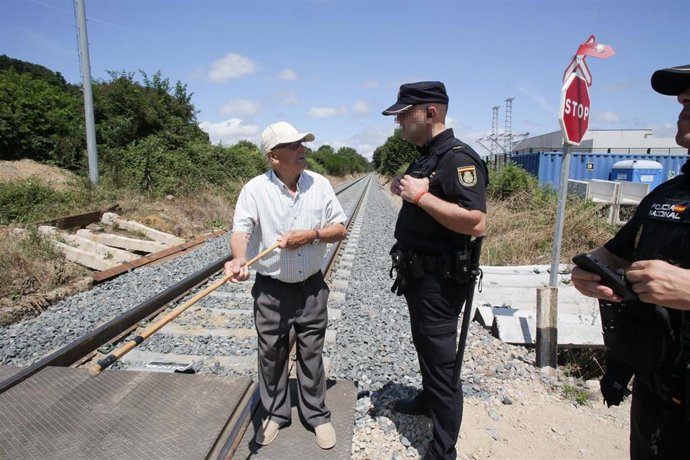 Archivo - Un agente de Policía Nacional conversa con un vecino de las parroquias de Coeo y Recimil durante una concentración donde han cortado la vía del tren en la que fallecieron dos jóvenes al cruzar el paso a nivel, a 19 de julio de 2023, en Recimil