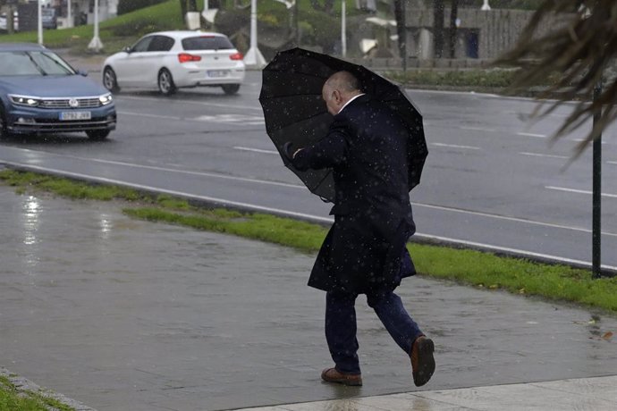 Un hombre con paraguas trata de refugiarse del viento y de la lluvia, a 4 de noviembre de 2023, en A Coruña, Galicia (España). La Agencia Estatal de Meteorología (AEMET) ha activado en A Coruña el aviso rojo por la llegada de la borrasca Domingos, que p