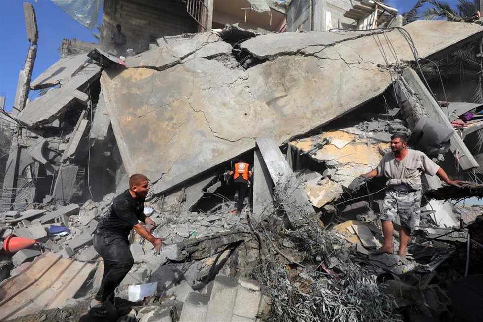 Un grupo de palestinos busca entre los escombros de un edificio en la Franja de Gaza