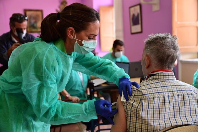 Imagen de archivo de una profesional sanitaria vacunando a una persona mayor.