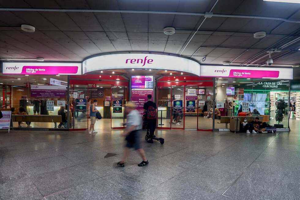 Archivo - Viajeros pasan por delante de la oficina de Renfe, en la estación de Atocha