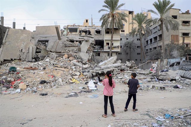 GAZA, Nov. 13, 2023  -- Children stand beside the rubble of buildings destroyed in Israeli airstrikes in the southern Gaza Strip city of Khan Younis on Nov. 12, 2023. 