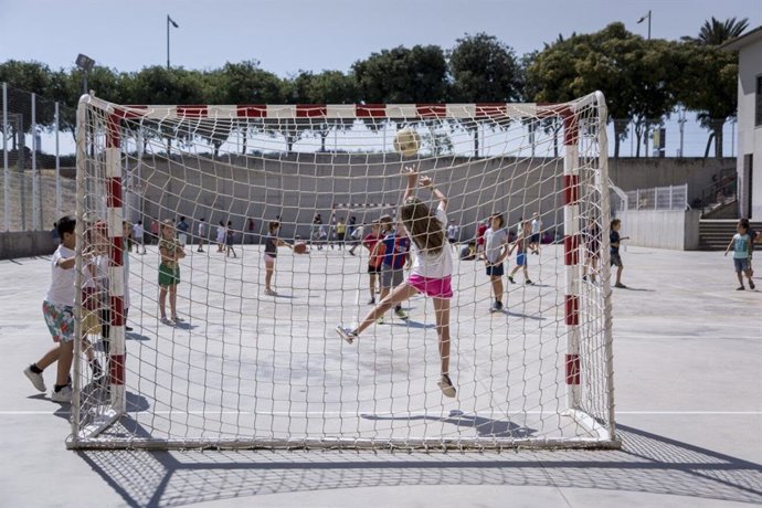 Niños juegan a fútbol en un patio escolar.
