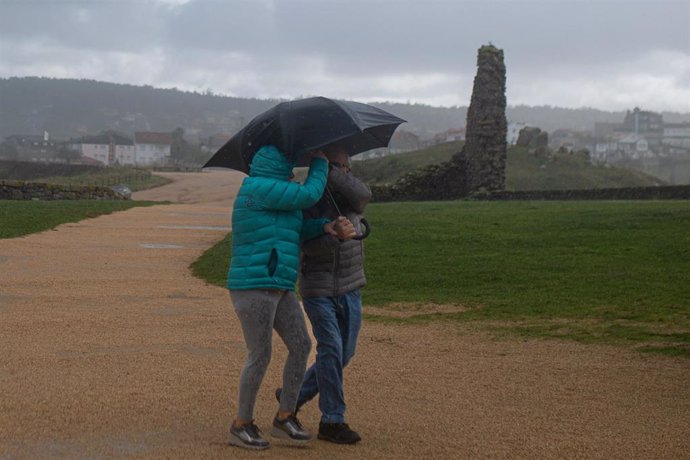 Dos personas se protegen de la lluvia con un paraguas, en la playa de A Lanzada, a 5 de noviembre de 2023, en O Grove, Pontevedra, Galicia (España). La borrasca Domingos ha dejado en toda Galicia un total de 1.166 incidencias. En Pontevedra, fueron 438, l