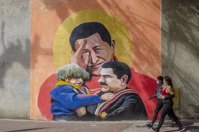 Archivo - December 6, 2020, Caracas, Venezuela: Two young girls walk in front of a graffiti of the late ex-president Hugo Chavez and the current president of Venezuela, Nicolas Maduro