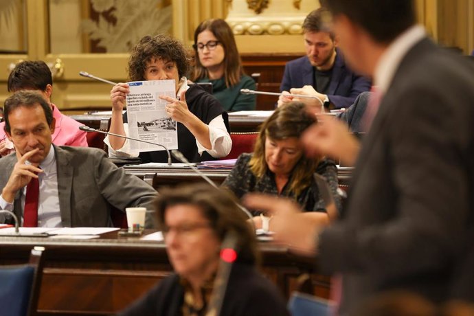 La diputada del PSOE Maria Pilar Carbonero i Sánchez muestra una noticia al conseller de Turismo mientras interviene durante un pleno en el Parlament balear.