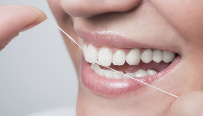 Archivo - Mujer cuidando sus dientes con seda dental.