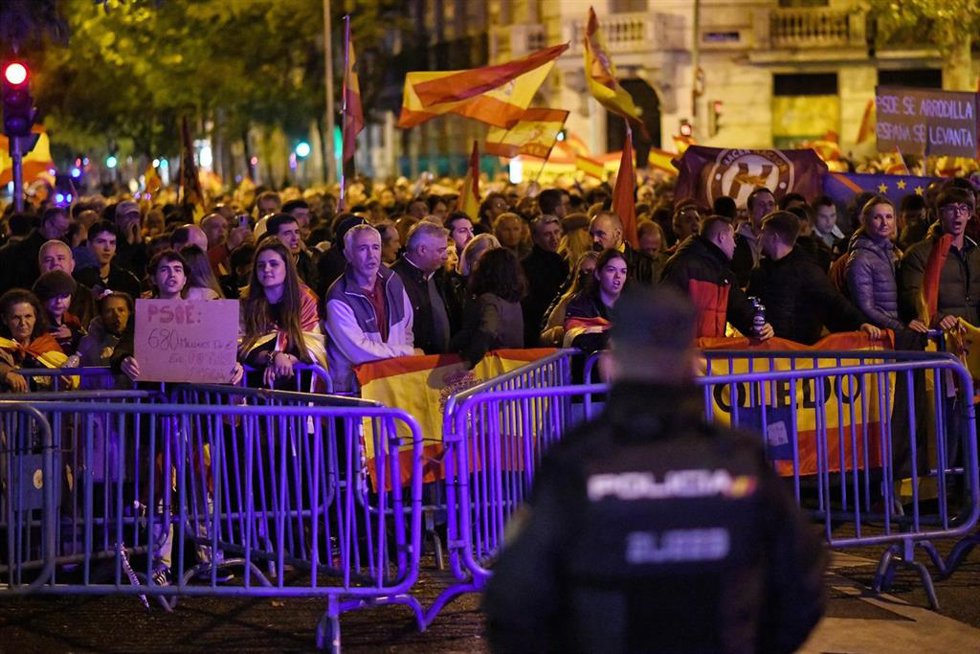 Decenas de personas con banderas y carteles, durante una protesta contra la amnistía, frente a la sede del PSOE, a 11 de noviembre de 2023, en Madrid (España).