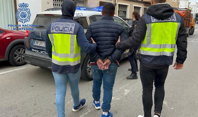 Dos agentes de la Policía Nacional acompañan a uno de los detenidos.