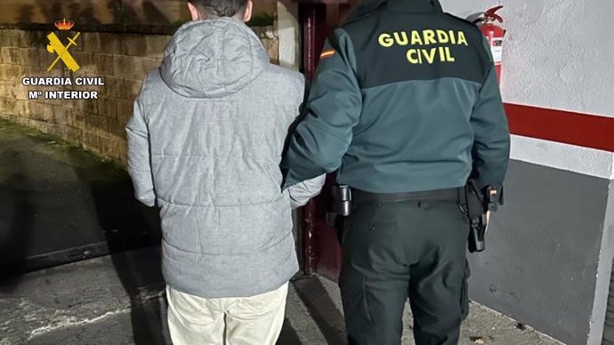 Un agente de la Guardia Civil junto a uno de los detenidos