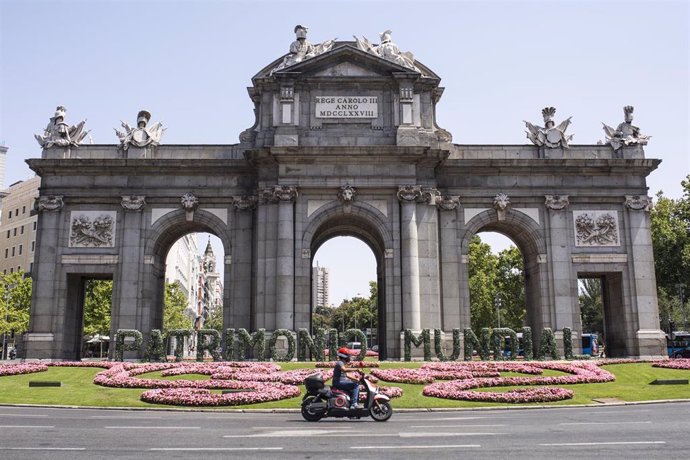 Archivo - Una moto pasa por las letras gigantes que forman la palabra Patrimonio Mundial en la Puerta de Alcalá