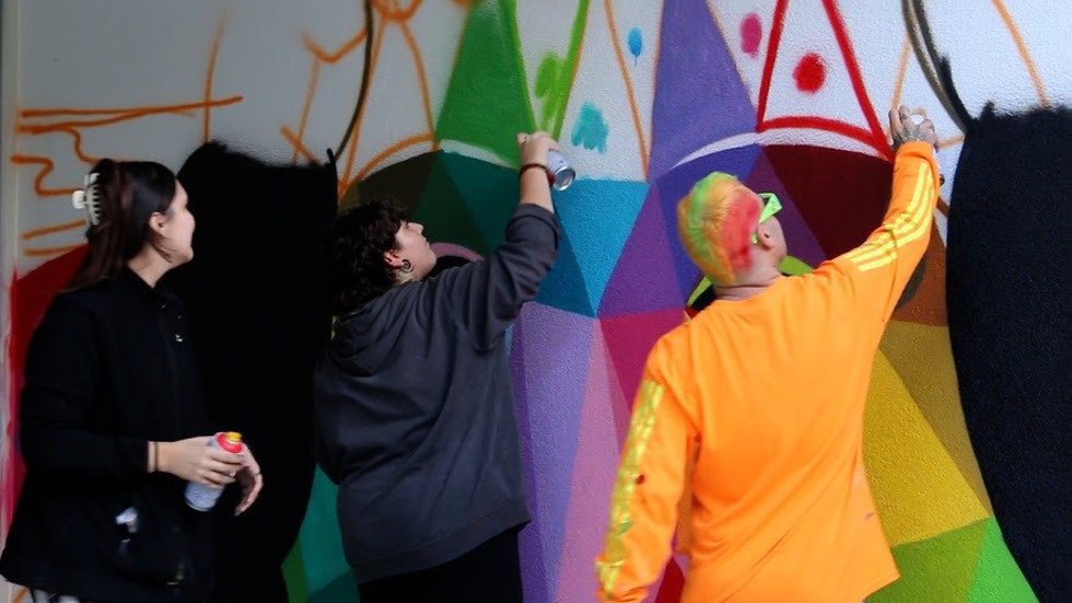 El artista Okuda San Miguel y dos menores pintando un mural por el Día de la Infancia.