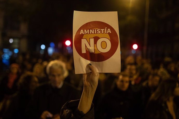 Una persona muestra un cartel, durante una protesta contra la amnistía, frente a la sede del PSOE, a 11 de noviembre de 2023, en Madrid (España). Miles de personas se han vuelto a concentrar frente a la sede del PSOE en la calle Ferraz en la novena jorn