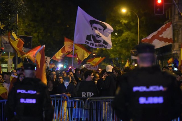 Decenas de manifestantes con banderas y carteles tras las vallas de seguridad y frente a varios agentes de policía, durante una manifestación contra la amnistía frente a la sede del PSOE en Ferraz, a 18 de noviembre de 2023, en Madrid (España). 