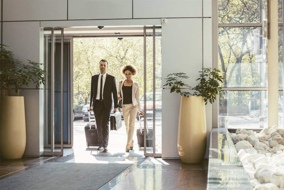 Archivo - Viajeros de negocios entrando en un hotel con sus maletas.