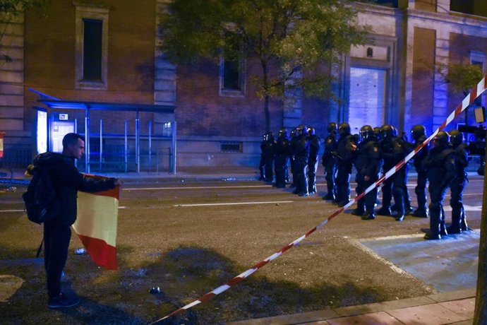 Un joven muestra una bandera española a varios agentes antidisturbios, durante una manifestación contra la amnistía frente a la sede del PSOE en Ferraz, a 18 de noviembre de 2023, en Madrid (España). 