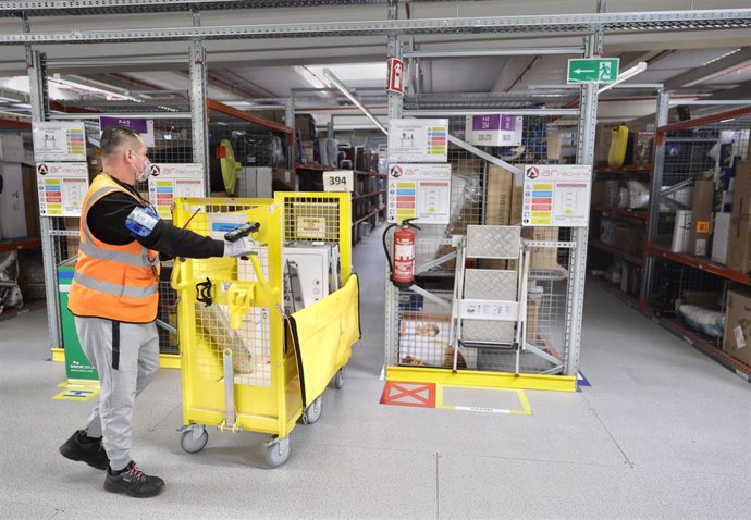 Archivo - Un trabajador prepara pedidos con un carro, en el interior de las instalaciones del Centro Logístico de Amazon 