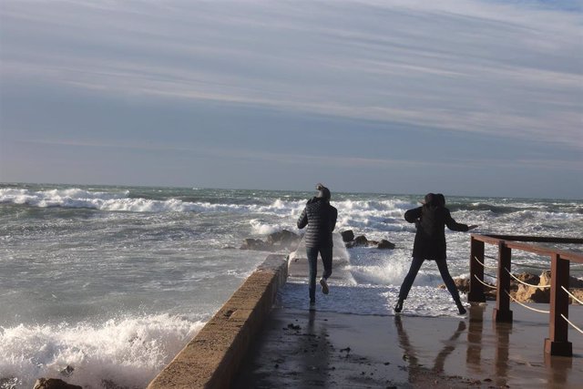 Archivo - Dos personas fotografían el oleaje causado por el viento, en enero de 2023, en Palma. 