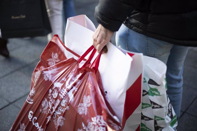 Archivo - Varias personas con bolsas de la compra en una calle céntrica 