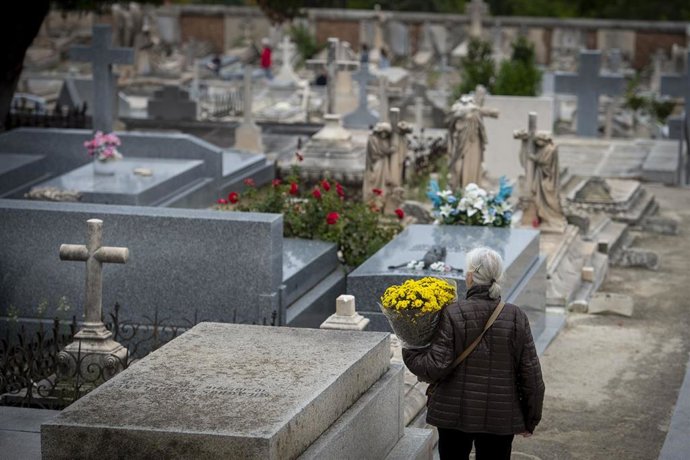 Una mujer lleva flores a un cementerio 
