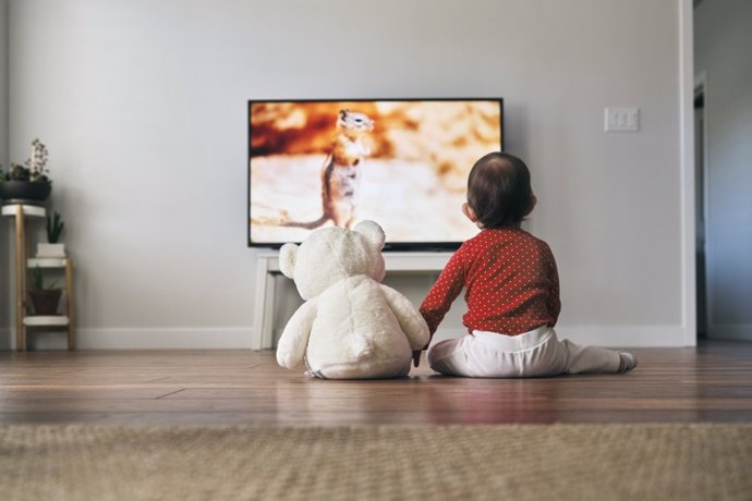 Archivo - Bebé viendo la tele con su oso de peluche