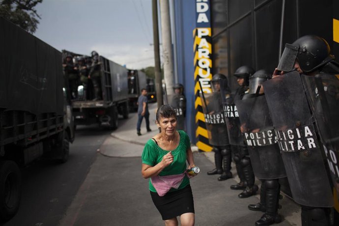 Archivo - Una mujer pasa frente a la Policía durante unas protestas en Guatemala 